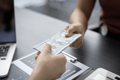 a person holding a money bill and a laptop