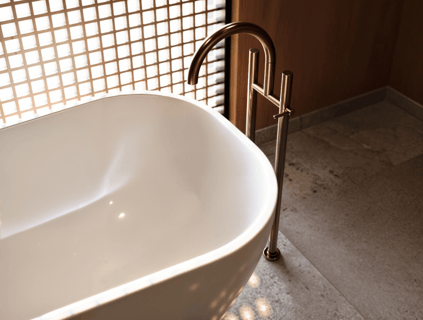 Minimalist white freestanding bathtub, bronze floor-mounted faucet.