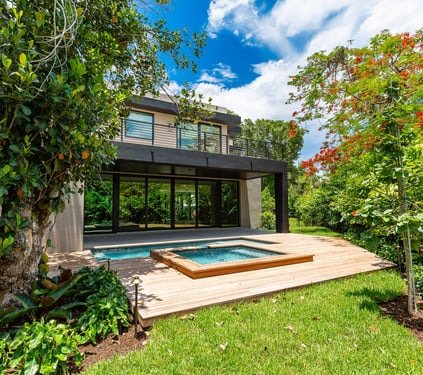 a medium sized luxury home backyard showing vibrant foliage, swimming pool with hot tub and deck