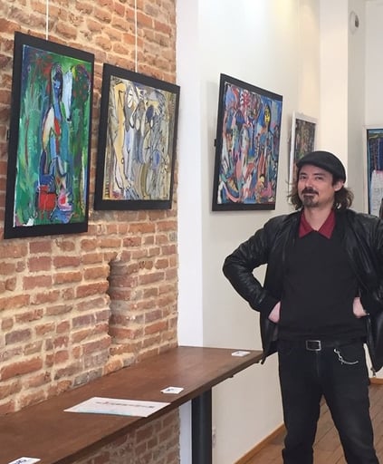 Julien Berger BERG debout devant ses tableaux dans la galerie le Bocal Toulouse