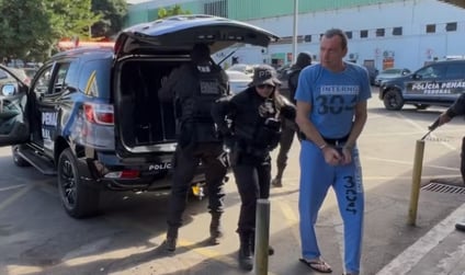 a man in a blue shirt is standing in front of a police car