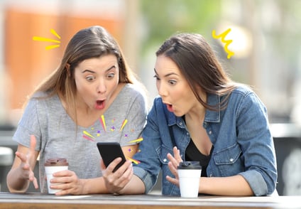 Two women gasping at what they see on their phone