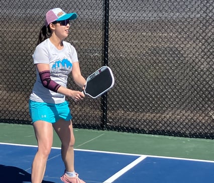 Ellen playing pickleball on an outdoor court, showcasing active Smart Dinker coaching in action.