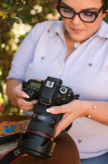 Fotógrafa Taty Pacheco olhando para sua câmera.