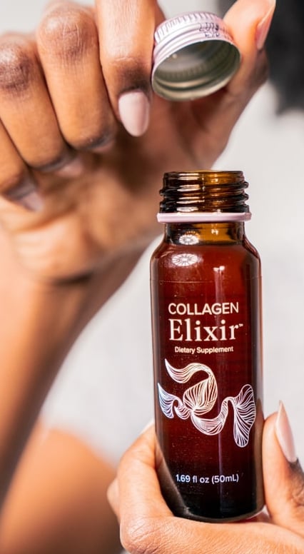 a woman holding a bottle of elixix elixixix