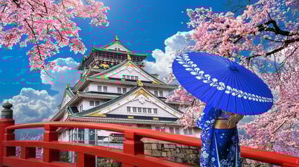 Osaka castle with cherry blossoms with woman in traditional kimono with umbrella