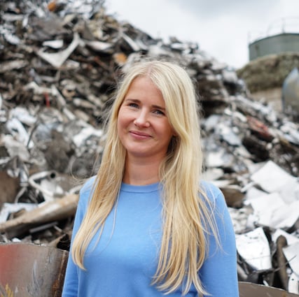 a woman in a blue shirt standing in front of a pile of rubble