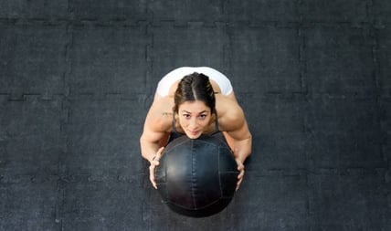 a woman doing a medicine ball exercise