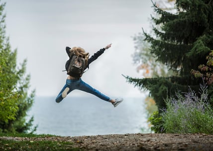 a woman jumping in the air with her hands up in the air