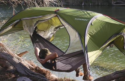 a person sitting in a hammock with a tent