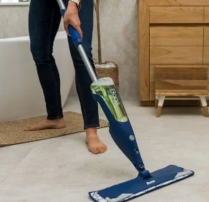 a woman is cleaning a tile floor with a mop