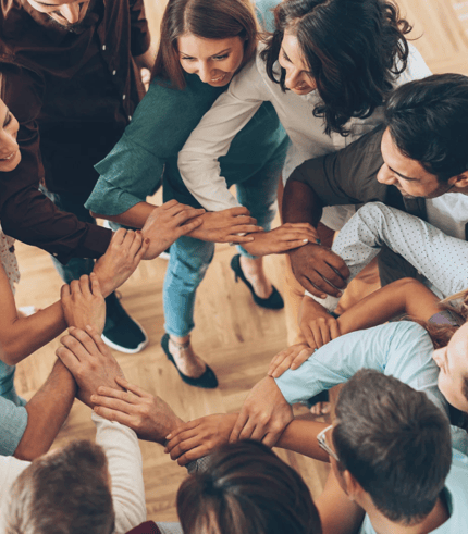 a group of people standing in a circle with their hands together