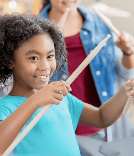 child smiling playing drums