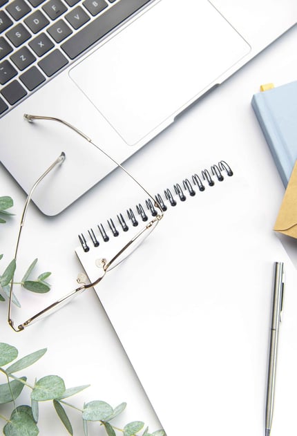 Image of a notebook with a laptop, glasses and eucalyptus leaves