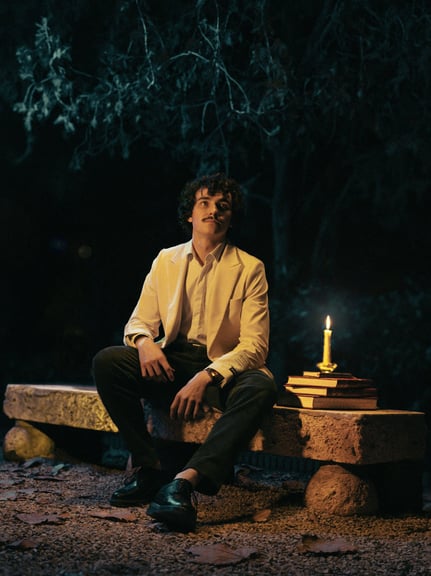 a man sitting on a bench with a candle lit up