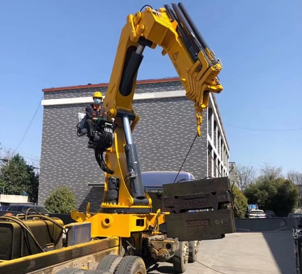 A large object being raised by a crane, specifically a 25 Ton Knuckle Loader Crane.