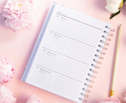 un cahier avec un stylo et un crayon et un stylo sur fond rose