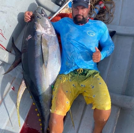  A man in a blue shirt is holding a huge yellowfin tuna on a Zanzibar fishing charter