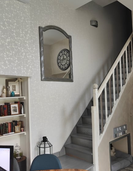 Miroir à cadre métal sur mur gris clair et escalier blanc