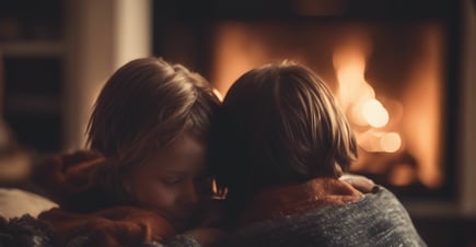 dos niños sentados en un sofá frente a una chimenea