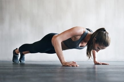 a woman doing push ups on a plank board