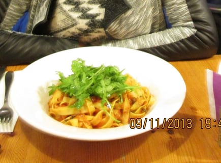 femme assise au restaurant devant une assiette de pâtes 