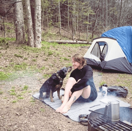 Chels from the rewilding podcast and their dog carlo camping outside