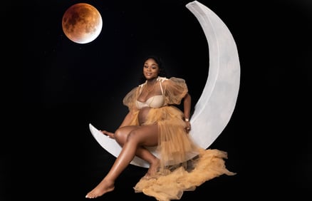 a pregnant woman sitting on a moon shaped moon