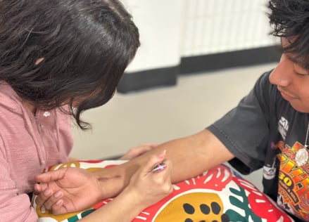 young woman applying henna to forearm of smiling young man