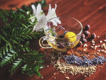 a cup of tea with on a wood table with flowers in it