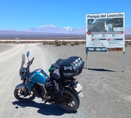 a motorcycle parked on a dirt road near a sign