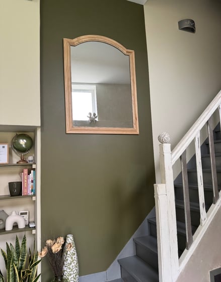 Miroir à cadre bois clair sur mur vert olive et escalier repeint