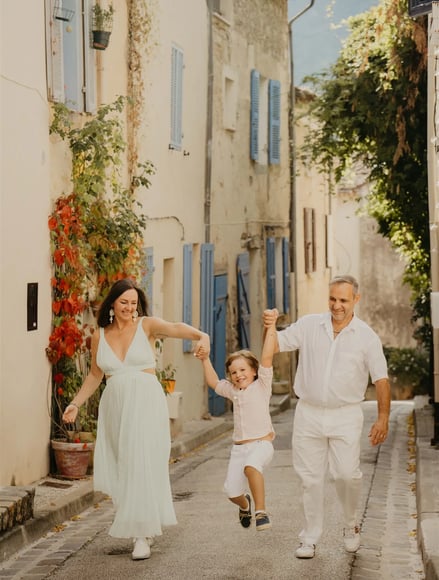 Parents jouant avec leur enfant dans une ruelle de village – séance photo de famille naturelle Gard
