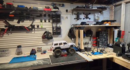 White RC truck on a workbench with tools and bin on pegboard.