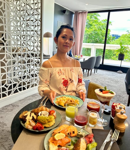 a woman sitting at a table with food and drinks
