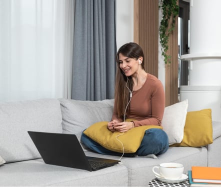 a woman sitting on a couch with a laptop and headphones