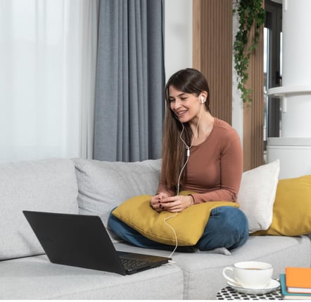 a woman sitting on a couch with a laptop and headphones