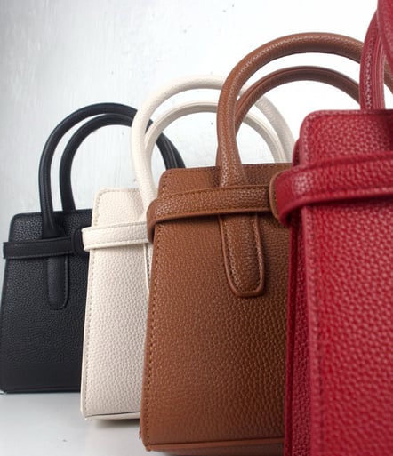 a row of four different colored handbags