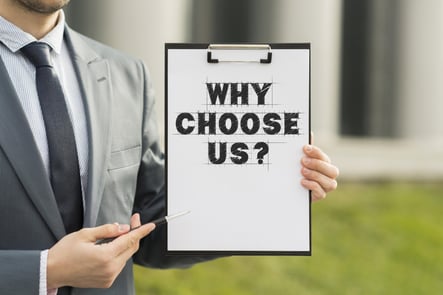 A man holding a paper with pad behind it stating Why choose US ? this image is used on national pneumatic systems website.
