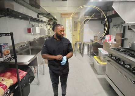 a man in a black shirt and blue jeans standing in a kitchen