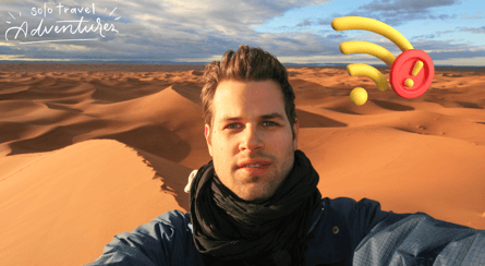 a man with a hat and scarf on a desert