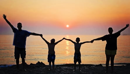 a family of four standing on a beach