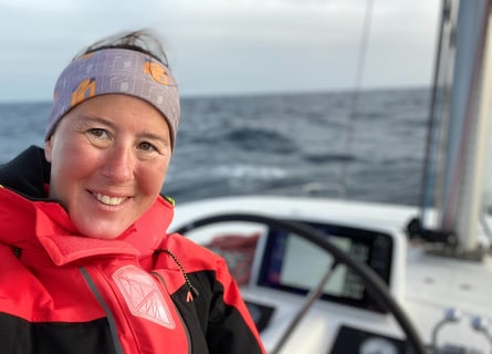 a woman smiling in a red jacket on a boat