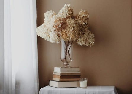 Vase de fleurs séchées sur des livres, symbole d’un espace calme, doux et conscient de ressourcement