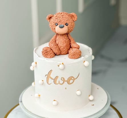 a teddy bear sitting on top of a cake