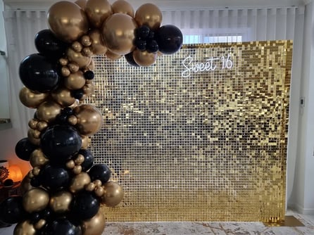 Gold shimmer wall with matching gold and black garland for sweet 16 in Brisbane.