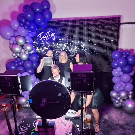 Group in the pimped out photo booth with black shimmer wall and balloon garland, Logan.