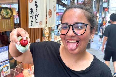 Trisha, a girl making a silly face with her tongue out and holding a Strawberry Mochi