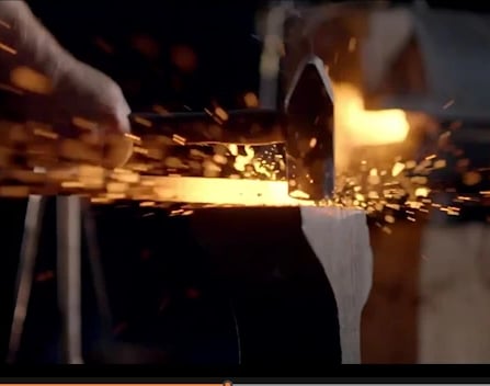 a person is using a hammer on g a piece of metal