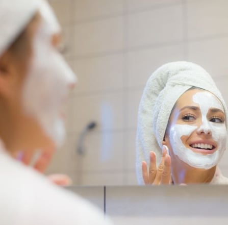 woman putting a cleansing mask on her face